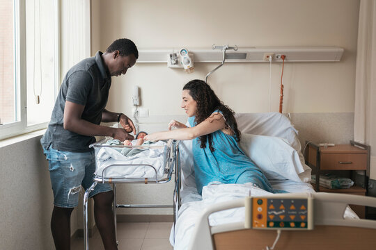 Multicultural couple in the hospital room after giving birth - Powered by Adobe