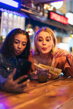 Girlfriends taking selfies while having a date at a street market