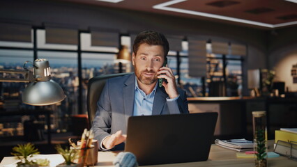 Late worker speaking phone at night workplace closeup. Office man discuss deal
