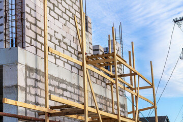 Process of building house from aerated concrete blocks. Scaffolding made of planks. Process of...