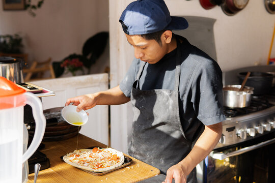 Young man preparing pizza in the kitchen.
