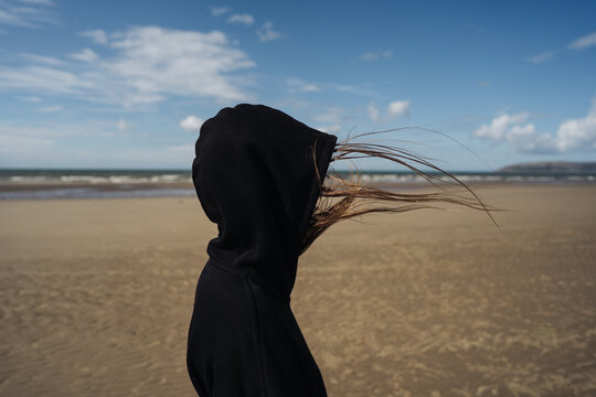 Woman in a hood on the beach