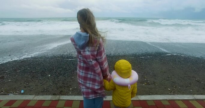A mother and her child are gazing out at the sea
