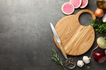 Flat lay composition with wooden cutting board and products on dark textured table. Space for text