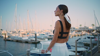 Romantic girl looking yachts moored at pier summer evening. Dreamy woman posing 