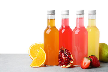 Delicious kombucha in glass bottles and fresh fruits on grey table against white background