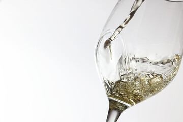 Pouring tasty aromatic wine in glass on white background, closeup. Space for text