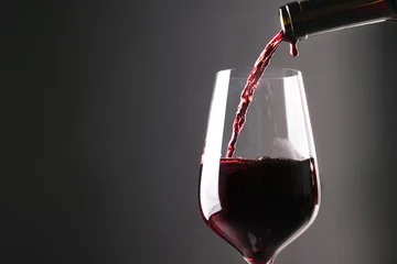 Fotobehang Pouring red wine into glass against grey background, closeup. Space for text © New Africa