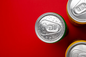Energy drinks in wet cans on red background, top view. Space for text