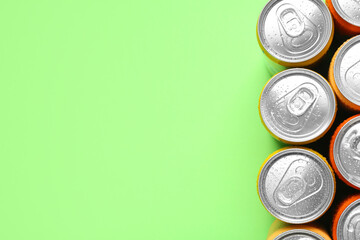 Energy drinks in wet cans on green background, top view. Space for text