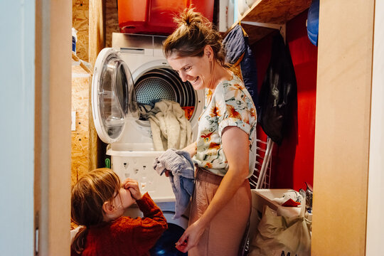 mother and daughter doing the laundry in messy laundry room