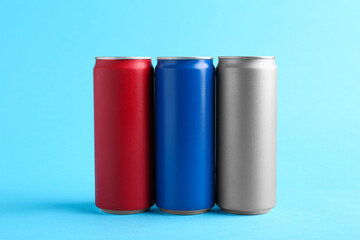 Energy drinks in colorful cans on light blue background