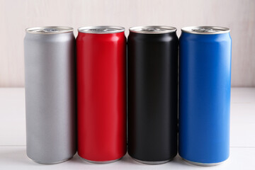 Energy drinks in colorful cans on white wooden table