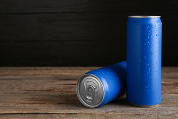 Energy drinks in wet cans on wooden table, space for text