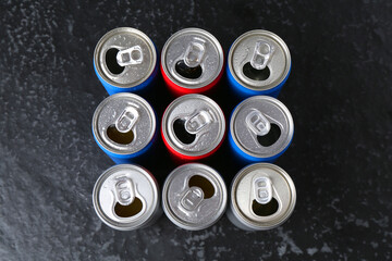 Energy drinks in wet cans on black textured table, flat lay. Functional beverage