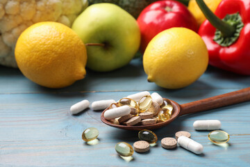 Dietary supplements. Spoon with different pills near food products on light blue wooden table, closeup