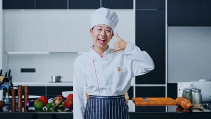 Asian Woman Chef Smiling And Making Call Me Gesture To Camera In Home Kitchen
