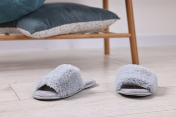 Grey soft slippers on light wooden floor indoors, closeup