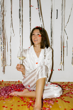 A young woman joyfully marvels at the confetti falling onto her 