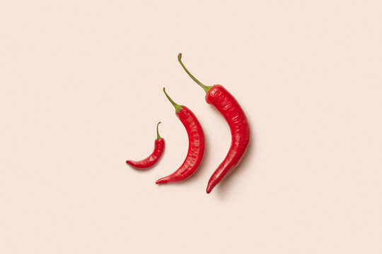 Top view of three various chili peppers on pastel background