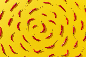 Fresh chili peppers arranged in spiral on yellow background