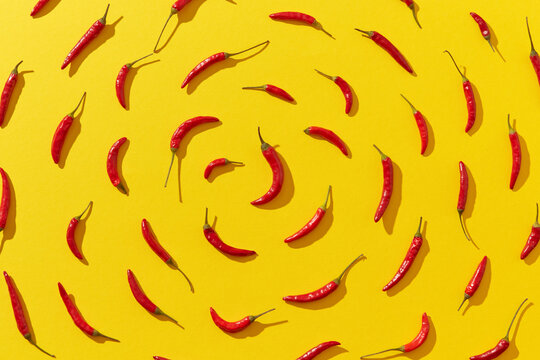 Fresh chili peppers arranged in spiral on yellow background