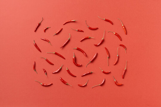 Top view of chili peppers arranged in rectangle on red background