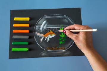 Soft pastel painting of fish in the bowl, with colorfull crayons, top view desk