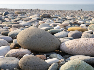 Gray sand and stones close-up on the beach. Stone in the foreground. Beach in winter. Sea coast soil.