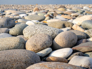 Gray sand and stones close-up on the beach. Stone in the foreground. Beach in winter. Sea coast soil.