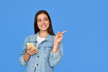 Happy pretty Latin gen z teen girl pointing aside with smartphone, smiling Hispanic customer using...