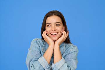 Excited pretty gen z Latin brunette teen girl, cute happy Hispanic student wearing denim jacket looking away with wow face expression standing isolated on blue background. Close up portrait.