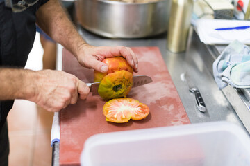 Detail of chef cutting fresh big tomato