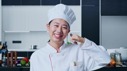 Close Up Of Asian Woman Chef Smiling And Making Call Me Gesture To Camera In Home Kitchen