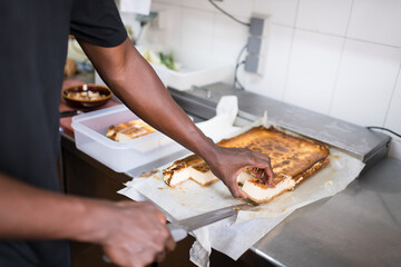 Chef cutting big cheesecake in restaurant kitchen
