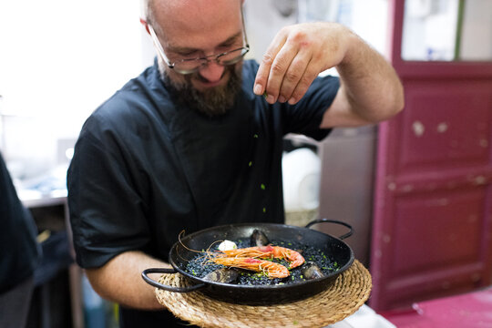 Satisfied chef seasoning black rice paella