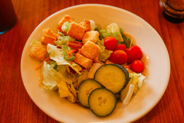 A fresh garden salad with lettuce, cumbers, tomatoes, and croutons as a healthy eating option in a cafe or restaurant for a healthy lifestyle. 
