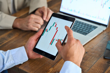 Financial advisor, crypto trader or business analyst holding digital tablet consulting stock market investor analyzing trade charts dynamic price or indexes invest trends on tab screen. Close up view.