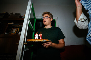 Guy carrying birthday pie in dark room