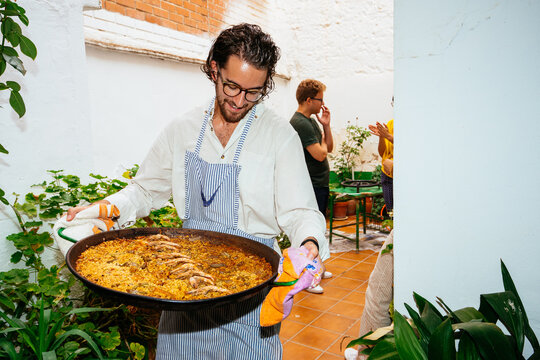 young bearded male carrying delicious paella