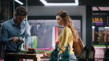 Clothing store assistant selling clothes making checkout cashier counter closeup