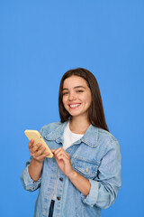 Smiling Latin teenage girl wearing denim jacket holding cellphone looking at camera. Happy Hispanic...