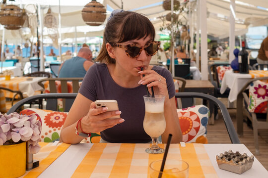 Woman drinking latte and using mobile phone in restaurant