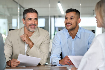 Happy busy business people talking at meeting table. Older Latin executive manager planning project...