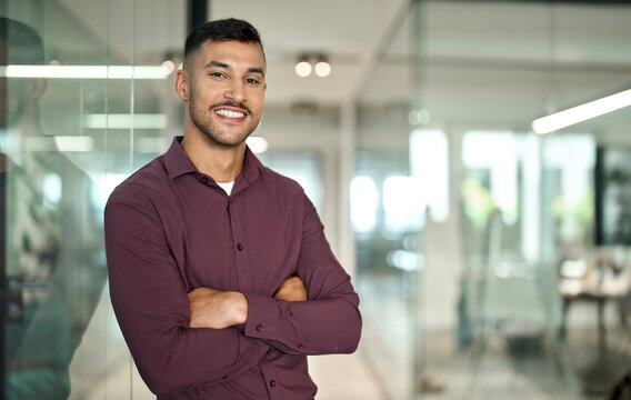 Confident young smiling Latin business man leader looking at camera standing arms crossed in office. Successful happy businessman manager, professional executive or male entrepreneur, portrait.