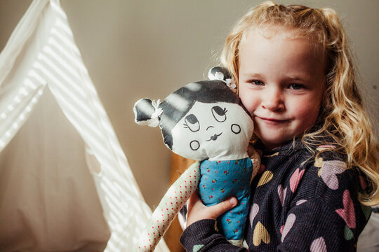 Girls cuddles a cloth doll in against face 2.