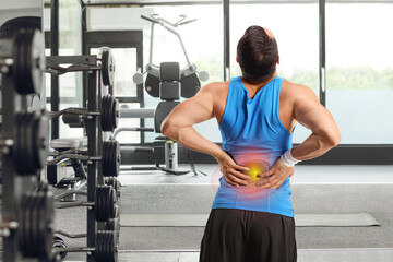 Rear view shot of a man at a gym holding his back