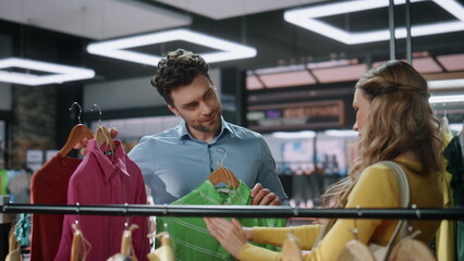 Man assisting client lady in fashion boutique closeup. Couple customers shopping