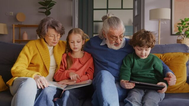 Grandmother helping girl reading book next to man and boy