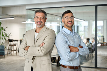 Fototapeta na wymiar Two happy successful business partners, male company team leaders, smiling professional confident managers standing back to back arms crossed in corporate office looking at camera. Portrait.